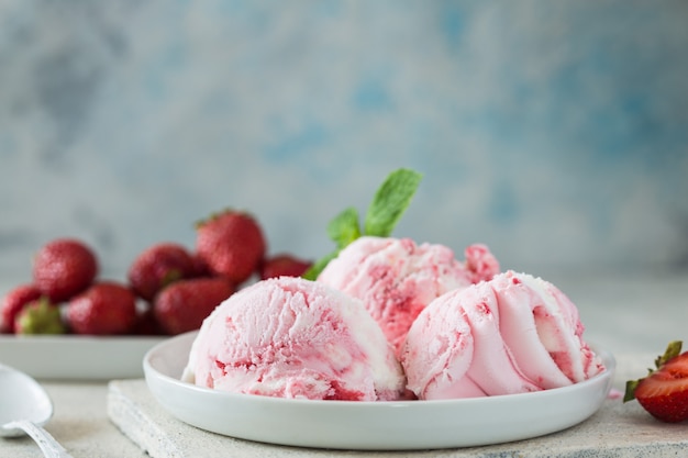 Trio de sorvete de sobremesa congelada com sabor de baunilha e morango saboroso em uma tigela com hortelã em uma pedra