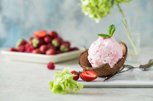 Foto trío de sabroso helado de postre helado con sabor a vainilla y fresa en un tazón de coco con menta en una piedra