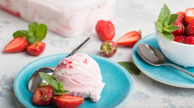 Trío de sabroso helado de postre helado con sabor a vainilla y fresa en un tazón con menta en una piedra