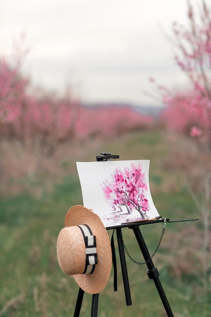 Tripé do artista com uma foto em uma primavera de pomar de pêssego