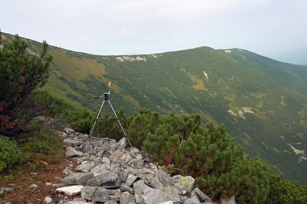 Trípode fotográfico en camino pedregoso de montaña