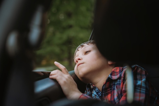 Triste aburrido muchacho caucásico viajando en coche sentado junto a la ventana abierta