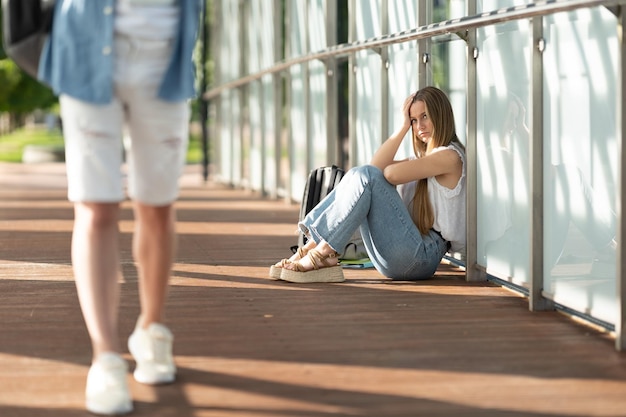 Triste adolescente estudiante chica sentada en un pasillo