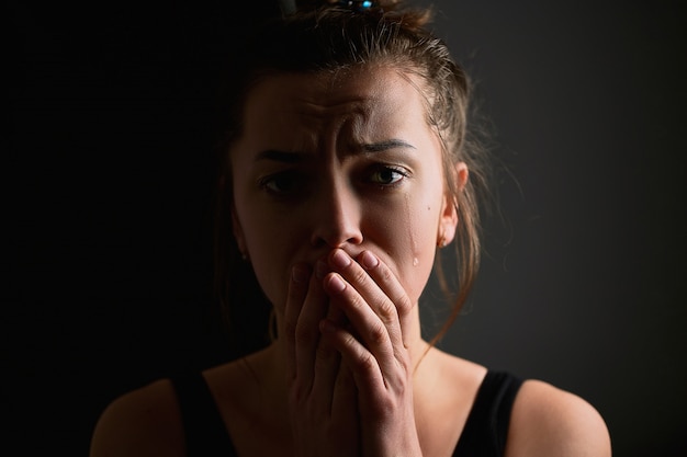 Foto triste afligida miserable desesperada mujer llorando con lágrimas, ojos y manos juntas