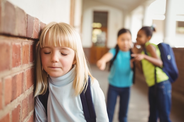 Foto triste alumno siendo intimidado por compañeros de clase en el pasillo