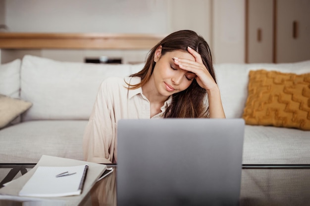 Triste y cansada jovencita asiática pensando en dormir en una laptop que sufre de estrés por exceso de trabajo