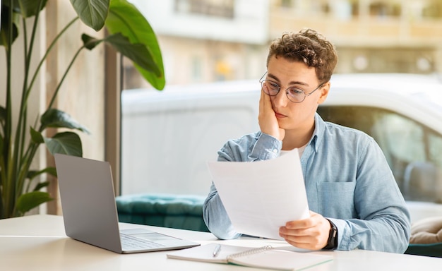 Triste cansado confundido millennial chico europeo estudiante gerente con portátil estudio de trabajo