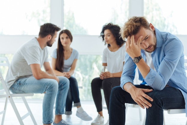 Triste deprimido triste hombre sentado en la silla y sosteniendo su cabeza sin saber qué hacer