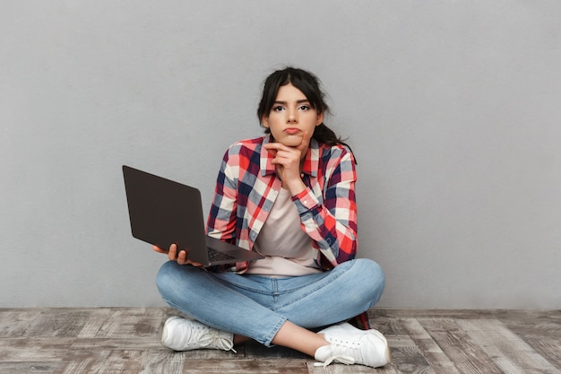 Triste descontente jovem estudante usando computador portátil.