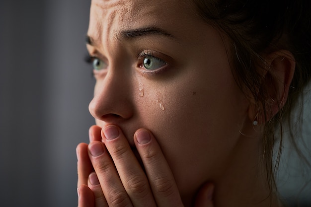 Foto triste desesperada mulher chorando com as mãos postas e lágrimas olhos