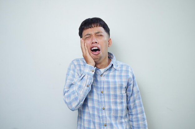 Triste expresión facial del hombre asiático con dolor sosteniendo la mejilla