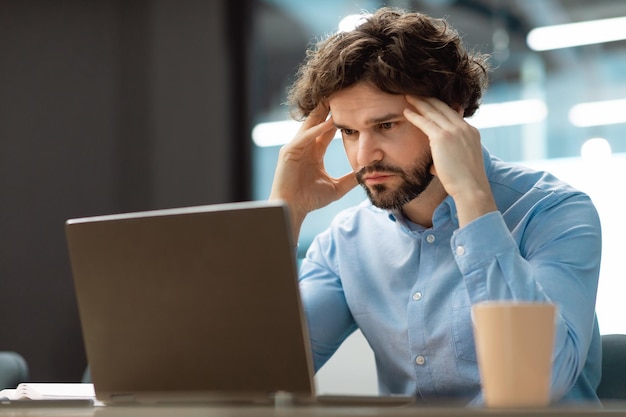 Triste hombre de negocios agarrando la cabeza usando pc