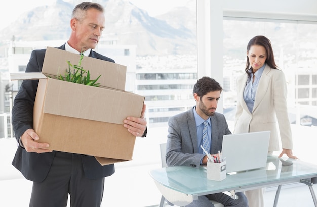 Triste hombre de negocios llevando una caja