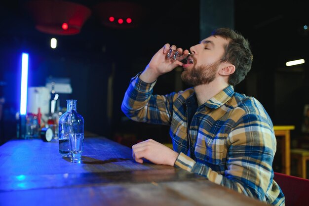 Foto triste hombre sentado en el mostrador de la barra de adicción al alcohol