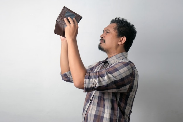 Triste homem asiático verificando sua carteira vazia