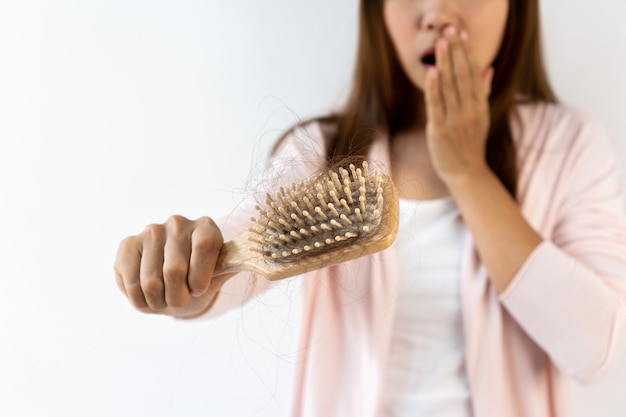 Triste joven asiática con problema de pérdida de cabello. Aislado sobre fondo blanco. De cerca