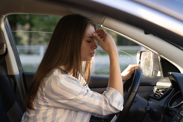 Triste joven cansada conduciendo un coche conductor de niña infeliz deprimido y ansioso mantenga el volante