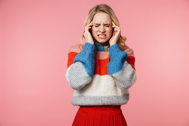 Triste joven mujer muy hermosa con dolor de cabeza posando aislado sobre pared rosa