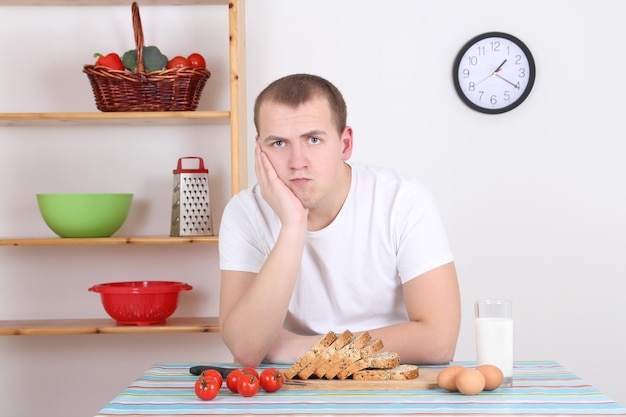 Triste joven sentado en la cocina