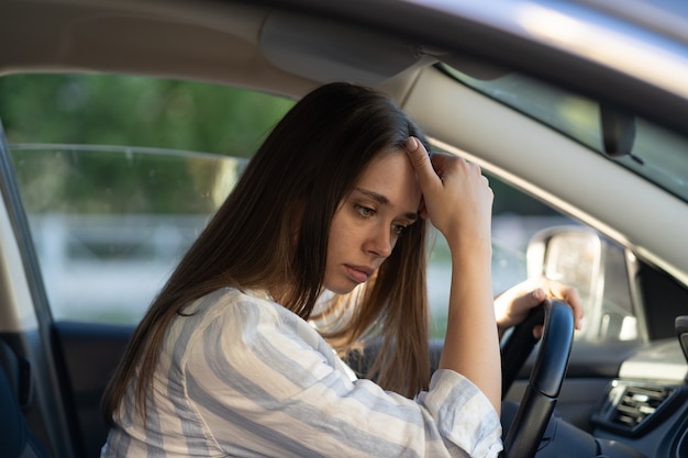 Triste joven sufre estresado conducir coche infeliz mujer conductora piensa en problema en el trabajo o estudio