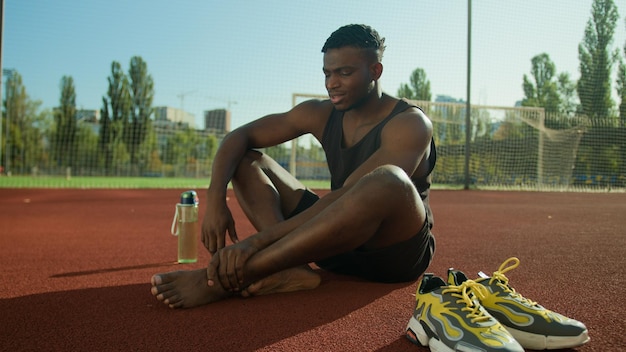 Foto triste mal-estar homem afro-americano desportista corredor atleta futebolista sofrendo doloroso pé danificado