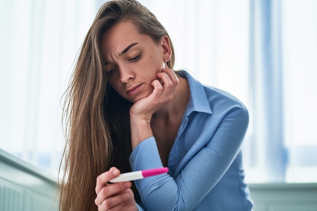 Foto triste mujer frustrada tiene prueba de embarazo con resultado negativo