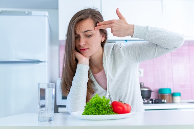 Triste mujer infeliz está cansada de hacer dieta, exterminarse con una dieta y obligarse a comer alimentos orgánicos, limpios y saludables