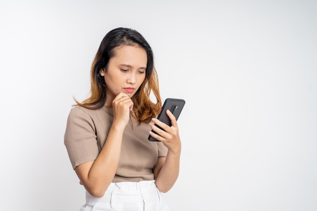 Triste mujer joven asiática mientras usa el teléfono móvil