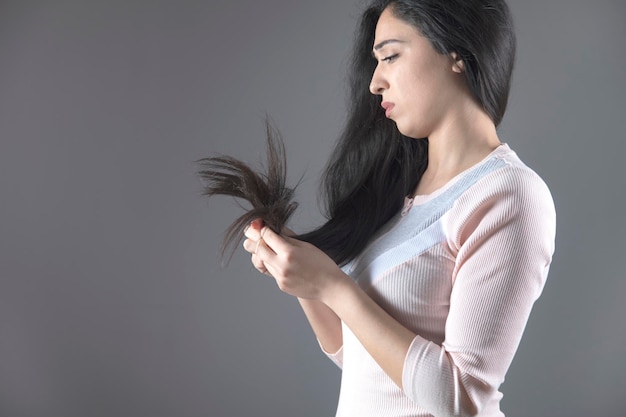 Triste mujer mano cabello dañado