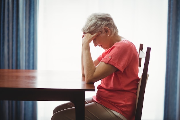 Triste mujer mayor sentada en una mesa