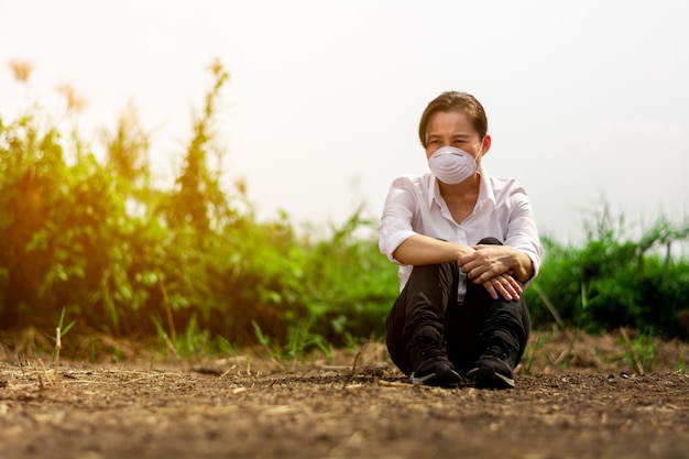 Triste mujer que llevaba una máscara en el área abandonada. Protección contra virus, infecciones, gases de escape y emisiones industriales.