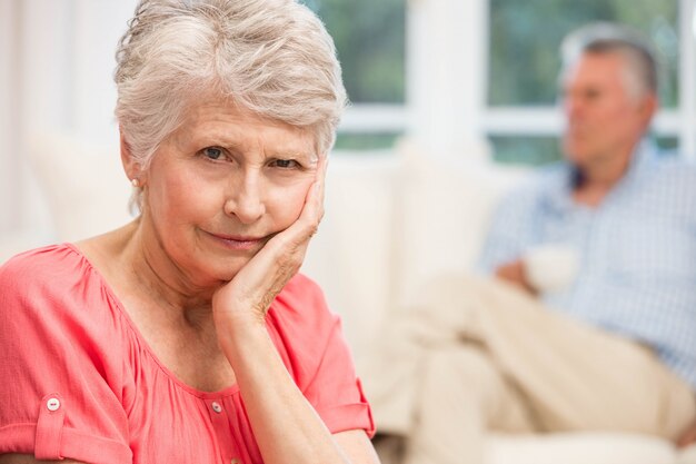 Triste mujer senior después de discutir con el esposo en la sala de estar