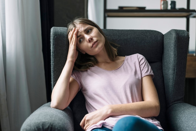 Triste mujer sentada en un sillón