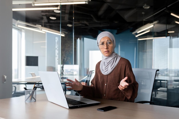 Triste mulher desapontada em hijab olhando para câmera empresária no local de trabalho não satisfeita com