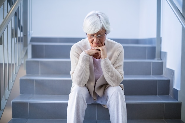 Triste mulher idosa sentada na escada