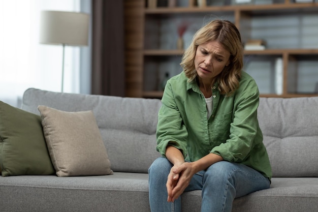 Triste mulher madura sênior sentada no sofá na sala de estar esposa sofrendo divórcio deprimido