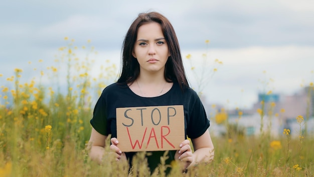 Foto triste mulher morena caucasiana patriota levanta cartaz com inscrição pare a guerra infeliz menina deprimida