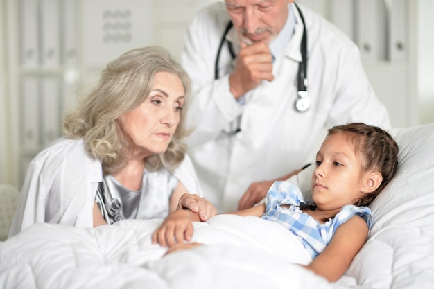 Triste mulher sênior com neta na enfermaria do hospital