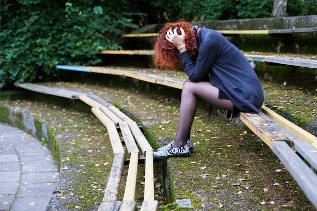 Foto triste mulher sentada no banco do parque