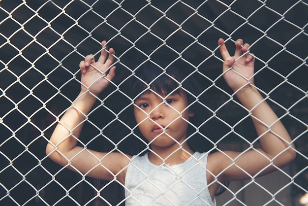 Foto triste niña asiática sola en jaula fue encarcelada, no hay libertad o falta de libertad