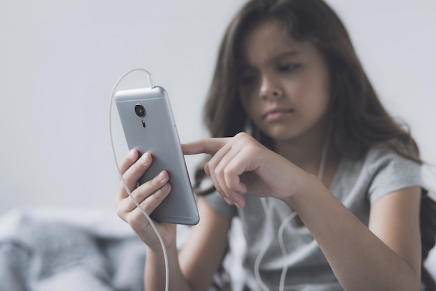 Foto triste niña está mirando el teléfono.