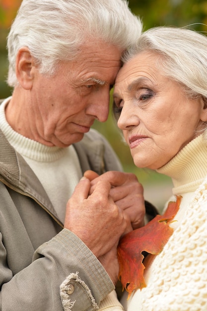 Triste pareja de ancianos abrazándose y posando en el parque de otoño