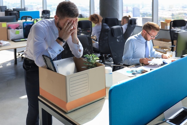 Triste trabajador despedido se lleva sus suministros de oficina de la oficina.