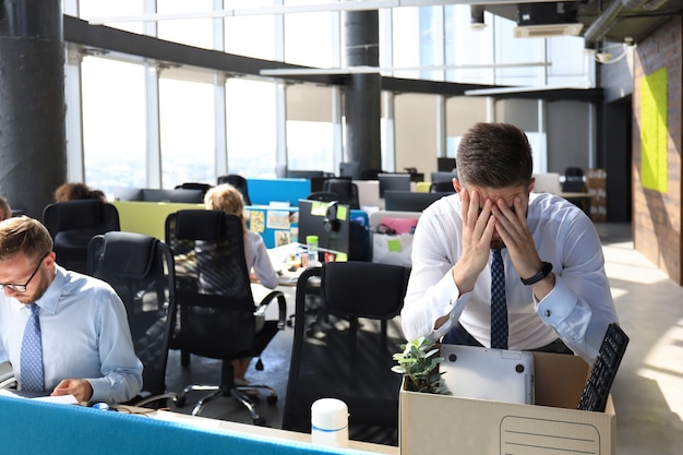 Triste trabajador despedido se lleva sus suministros de oficina de la oficina.