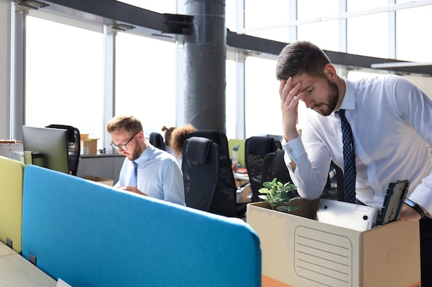 Triste trabajador despedido se lleva sus suministros de oficina de la oficina.