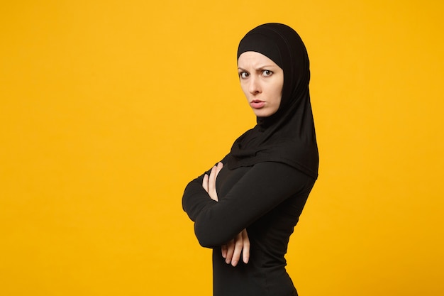 Triste triste chorar confusa jovem muçulmana árabe em roupas pretas de hijab posando isolado no retrato de parede amarela. Conceito de estilo de vida do Islã religioso de pessoas.