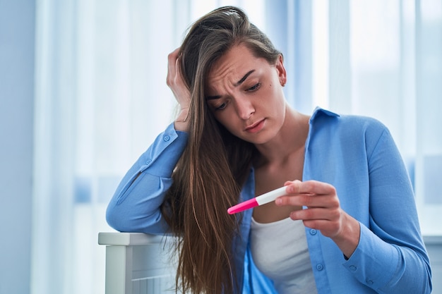 Triste triste mulher infeliz mantém teste de gravidez