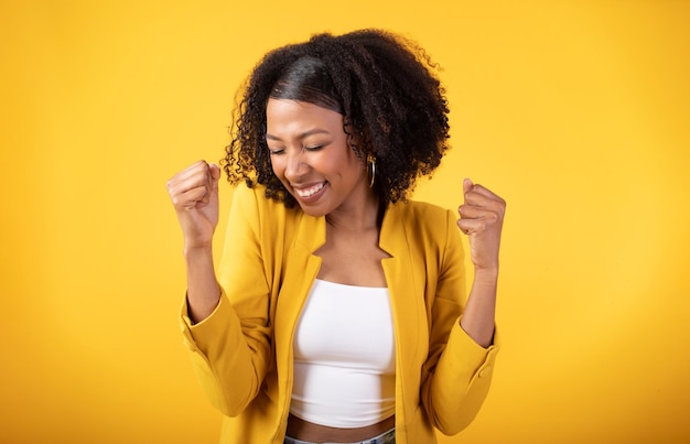 Triunfo empoderado mujer negra llena de alegría animando y celebrando la victoria agitando los puños apretados