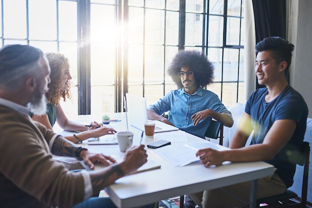 Troca de ideias Foto de um grupo de empresários criativos alegres reunidos em volta de uma mesa juntos dentro do escritório durante o dia