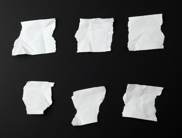 troceados trozos vacíos de papel blanco en un fondo negro de cerca